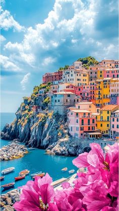 pink flowers are blooming in front of an island with buildings on the cliff side