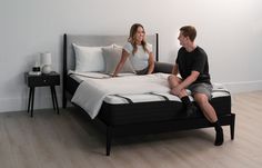 a man and woman sitting on top of a bed