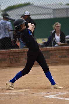 a woman in black and blue uniform holding a baseball bat