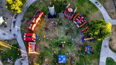 an aerial view of a carnival park with rides and people on the ground, inflatables and tents