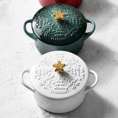 three different colored pots sitting next to each other on a white counter top, one with a gold star in the center