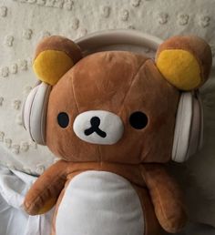 a brown teddy bear wearing headphones on top of a bed