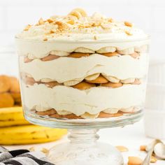 an image of a dessert in a glass dish on a white table with bananas around it