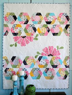 a quilted wall hanging next to two vases