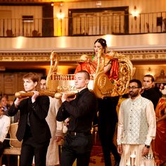 a group of people standing around each other in front of a crowd holding gold objects