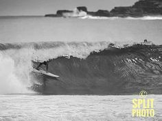 a man riding a wave on top of a surfboard in the ocean with waves behind him