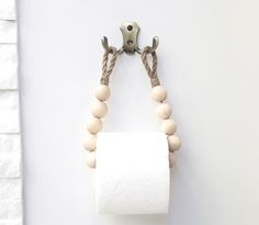 a roll of toilet paper hanging on a wall with two wooden beads attached to it