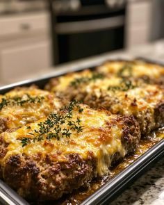 two meat patties covered in cheese and parsley on a baking sheet with an oven in the background