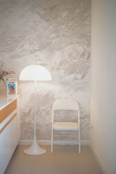 a white chair sitting next to a lamp on top of a table in a room