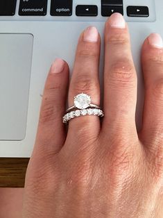 a woman's hand with a ring on her finger next to a laptop keyboard