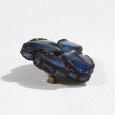 This is part of Chairish’s Costume Jewelry assortment.  This elegant Talosel or resin brooch pin was created by Line Vautrin in the 1950s. Features a freeform dimensional shape in black Talosel, encrusted with cobalt blue colored mirrored glass.  Glass and Talosel, a technique created by Line Vautrin, in which she used cellulose acetate that was fractured into tiny splinters and worked with heat. The creation process of Talosel jewelry involved many steps, including making the mirrors, coloring Blue Cabochon Brooch For Formal Occasions, Formal Blue Cabochon Brooch, Formal Blue Enamel Brooches, Mid-century Blue Brooches For Gifts, Unique Formal Enamel Brooch Pin, Unique Blue Brooches For Formal Occasions, Antique Handmade Blue Brooches, Antique Blue Enamel Brooches, Formal Blue Handmade Brooches