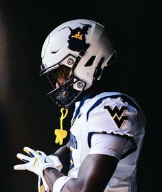 a football player wearing a white uniform and holding his hand out to the side with yellow letters on it