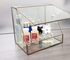 a clear box with some bottles on top of it and a flower in the middle