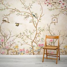 a chair sitting in front of a wall with flowers and birds painted on the walls