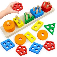 a child's hand is playing with wooden blocks and pegs on a white background