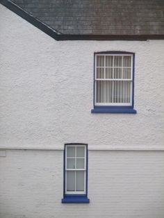 two windows on the side of a white building