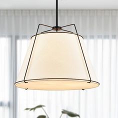 a white lamp hanging from a ceiling in a living room with two potted plants