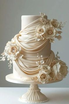 a three tiered wedding cake with flowers on top