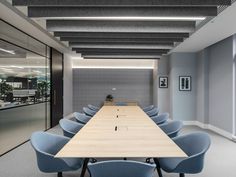 an empty conference room with blue chairs and a long table in the middle of it