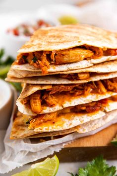 three quesadillas stacked on top of each other with limes and cilantro