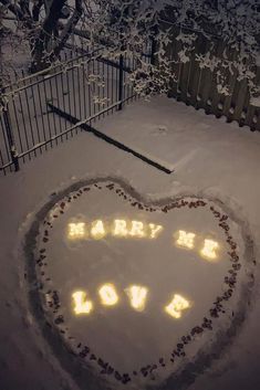 a lighted heart in the snow that says marry me, love is written on it