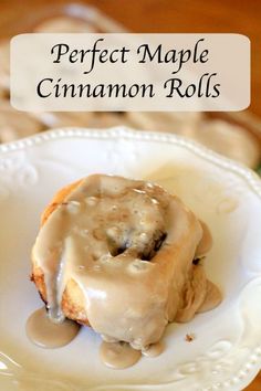 a white plate topped with a cinnamon roll covered in icing