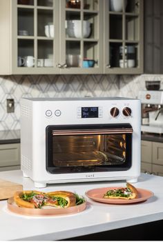 two pizzas sitting on plates in front of an oven