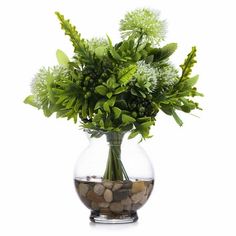 a glass vase filled with lots of green plants and rocks on top of it's side