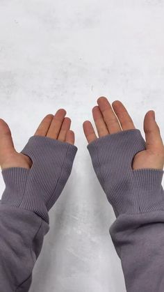 two hands wearing gray gloves with one hand in the air