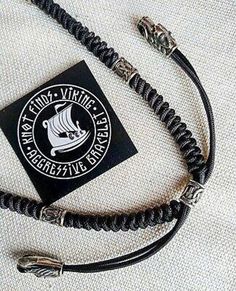 a black and silver bracelet with an emblem on the clasp, sitting on top of a white cloth