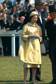 a woman in a yellow coat and hat standing next to a man wearing a suit