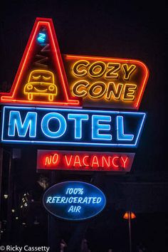 a motel sign lit up at night with the word cozy cone on it's side