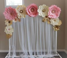 an arrangement of paper flowers is displayed in front of a window with sheer drapes