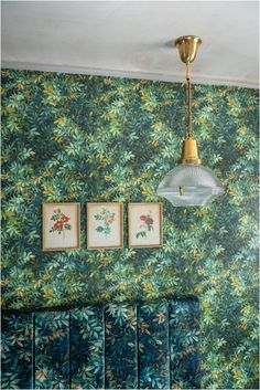 a lamp hanging from the ceiling in a room with green wallpaper and blue couches