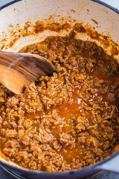 a wooden spoon stirring meat in a pot