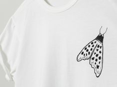 a white t - shirt with a black and white moth on it