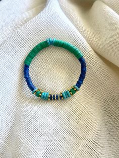 a blue and green beaded bracelet sitting on top of a white cloth