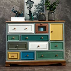 a multicolored dresser with two vases and a painting on the wall behind it