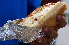 a person holding a piece of food in their hand with tin foil on the other side