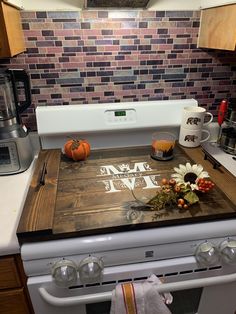 a wooden cutting board sitting on top of an oven in a kitchen next to a coffee maker