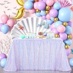 a table topped with balloons and cake next to a wall covered in confetti