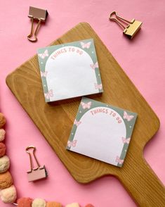 two things to do notepads sitting on top of a cutting board next to other items