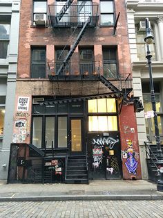 an apartment building with graffiti all over it's walls and stairs leading up to the second floor