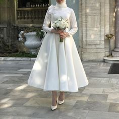 a woman wearing a white dress and holding a bouquet in front of an ornate building