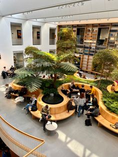 people are sitting and standing around in the lobby at an office building with plants growing on the walls