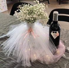 a wine bottle sitting on top of a table next to a vase filled with flowers