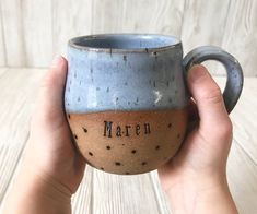 a hand holding a blue and brown coffee cup with the word maren on it