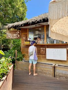 a woman standing in front of a small bar on a wooden deck with an umbrella over it