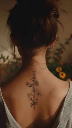 a woman with a flower tattoo on her back neck and behind her is a plant