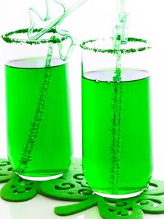 two glasses filled with green liquid sitting next to each other